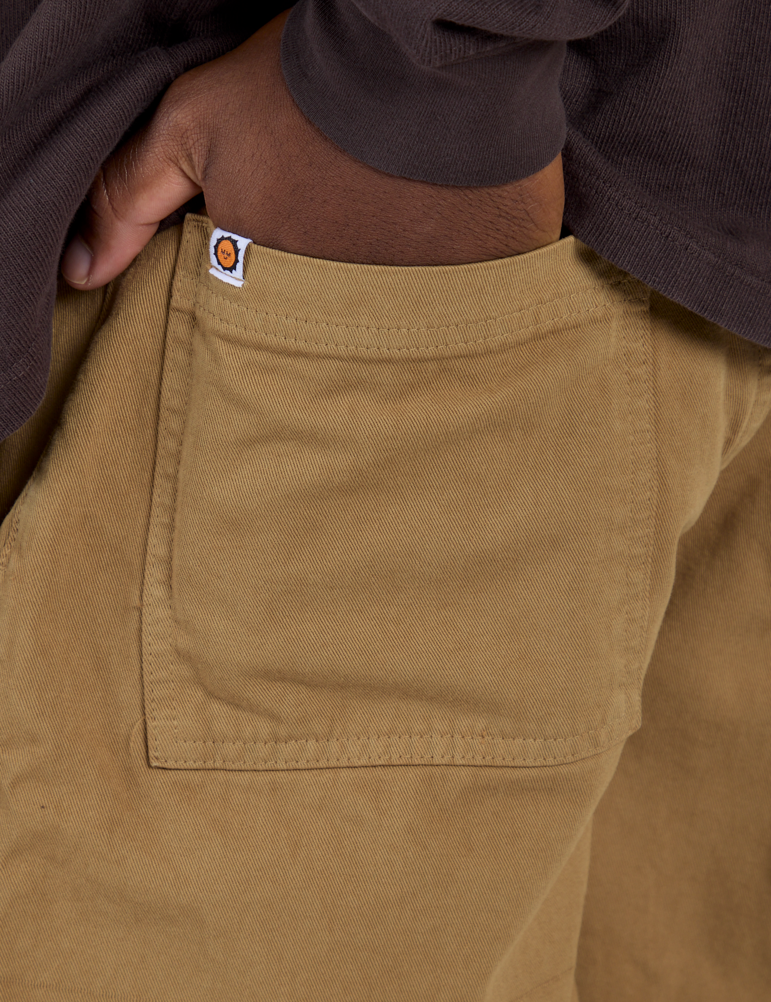 Close up of Isaac's hand in the front pocket of Longline Work Shorts in Desert Brown