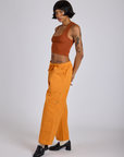 Side view of Drop Pocket Cargo Pants in Creamsicle Orange and burnt terracotta Cropped Tank on Kira