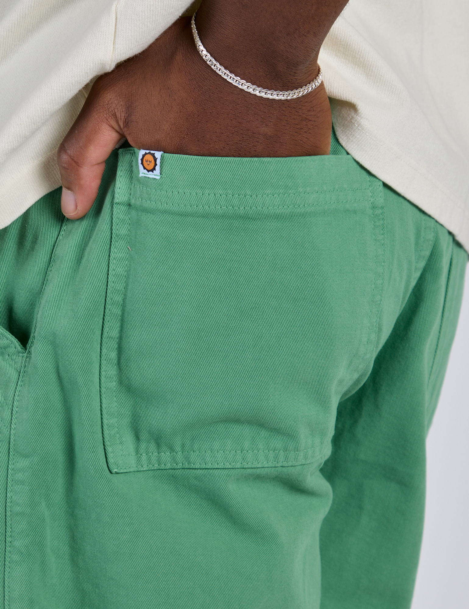 Close up of Isaac's hand in the back pocket of Longline Work Shorts in Seafoam Green