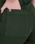 Close up of Alex's hand in the back pocket of Short Sleeve Jumpsuit in Swamp Green