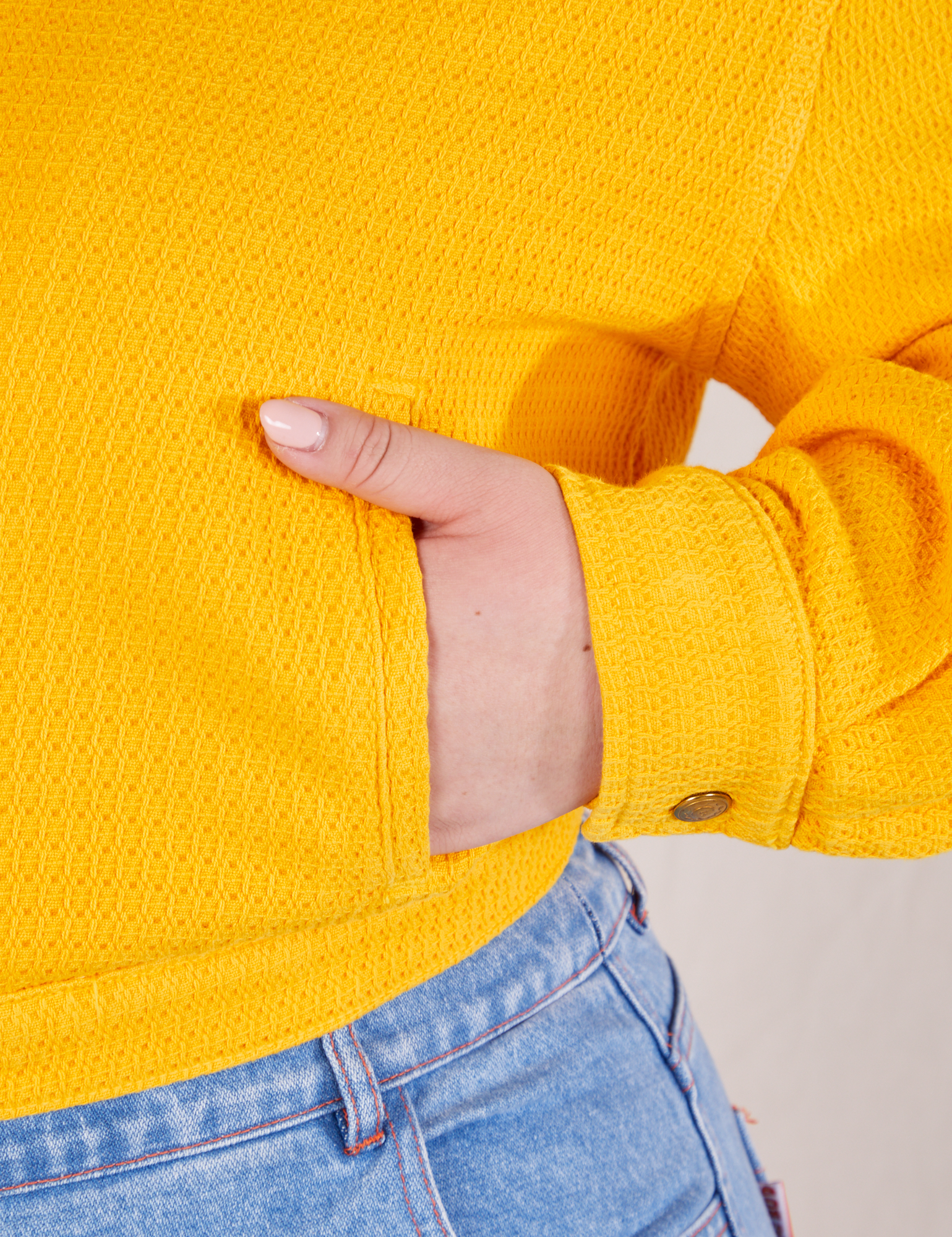 Front pocket close up of the Ricky Jacket in Sunshine Yellow. Ashley has her in the pocket
