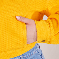 Front pocket close up of the Ricky Jacket in Sunshine Yellow. Ashley has her in the pocket