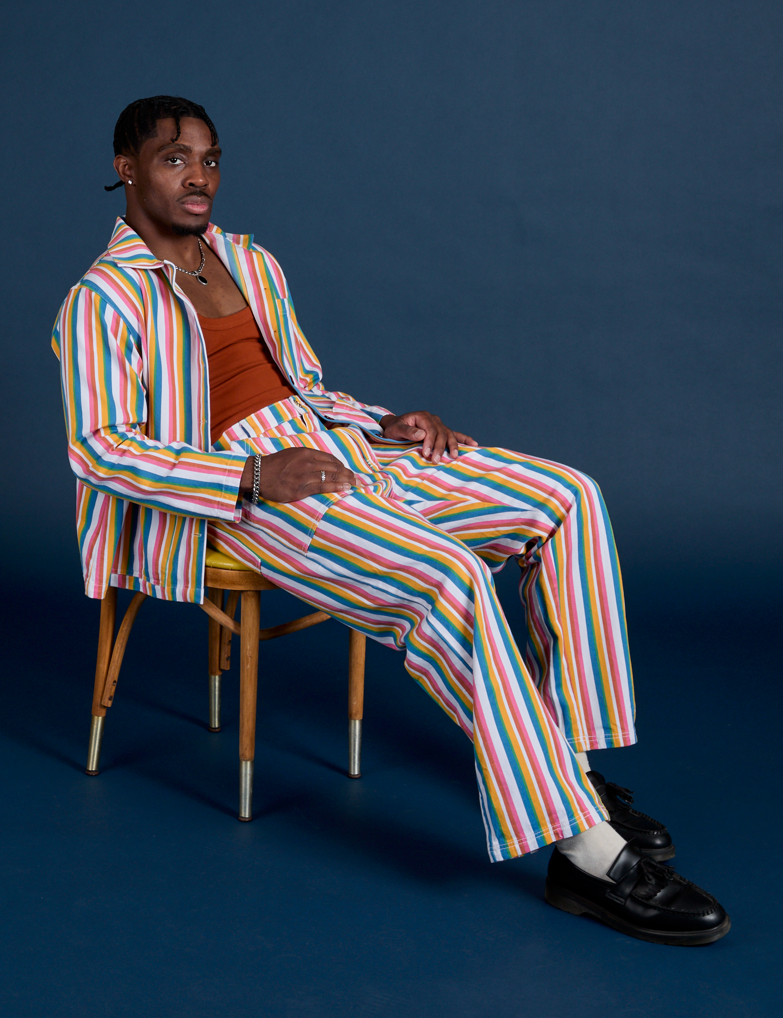 Isaac is wearing Stripe Work Jacket in Rainbow Striped matching Work Pants