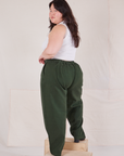 Angled back view of Heritage Trousers in Swamp Green and vintage off-white Tank Top on Ashley