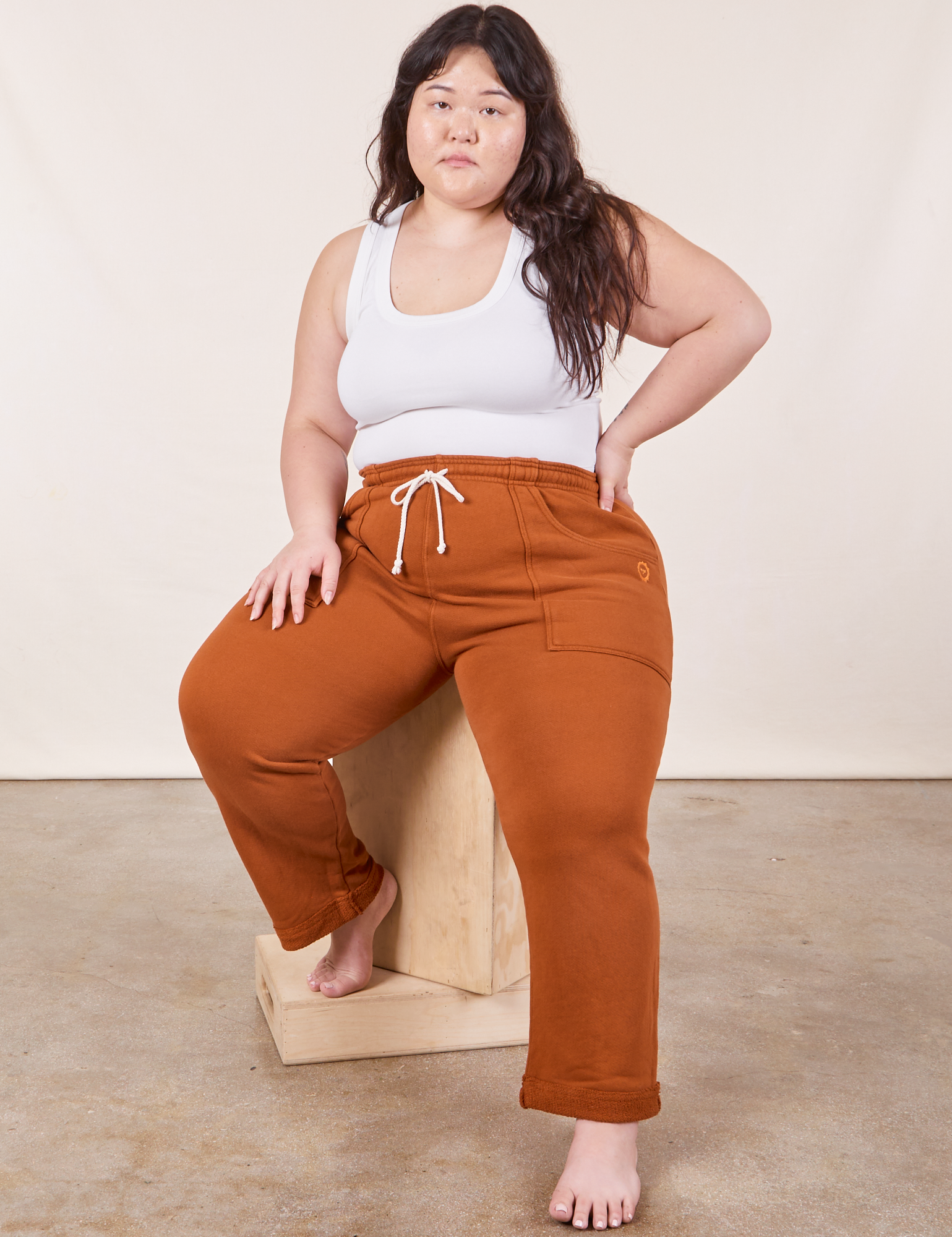 Ashley is wearing Cropped Rolled Cuff Sweatpants in Burnt Terracotta and vintage off-white Cropped Tank Top