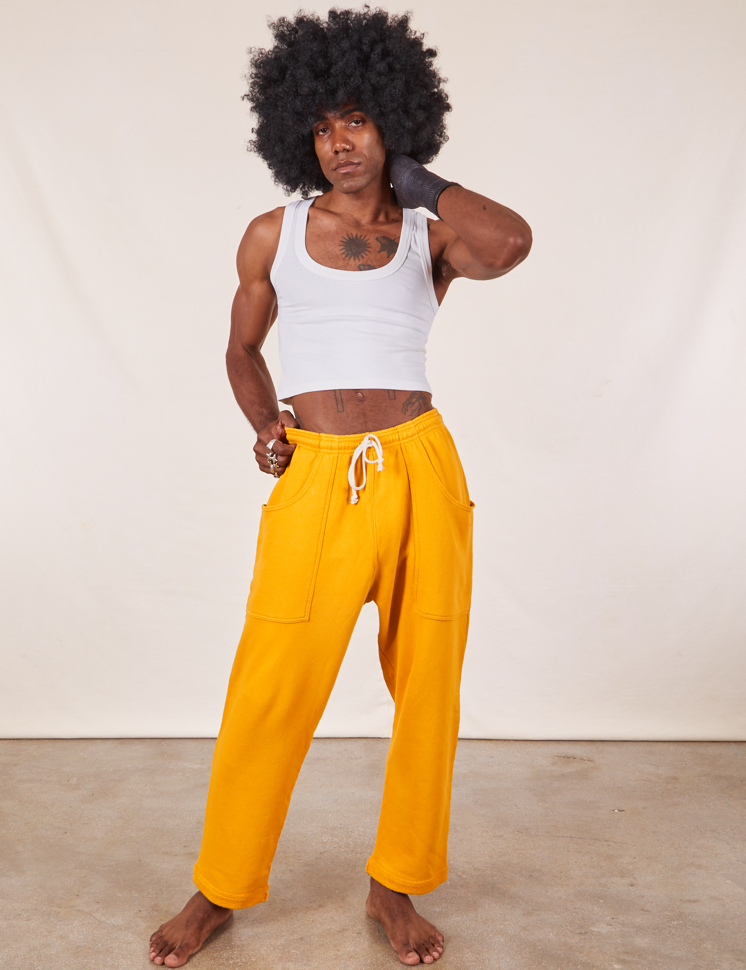 Jerrod is 6&#39;3&quot; and wearing M Cropped Rolled Cuff Sweatpants in Mustard Yellow paired with vintage off-white Cropped Tank Top