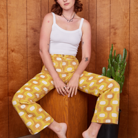 Alex is sitting on wooden box wearing Western Pants in Yellow Jacquard