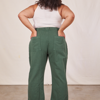 Back view of Western Pants in Dark Green Emerald and vintage off-white Tank Top. Alicia has both hands in the back pocket