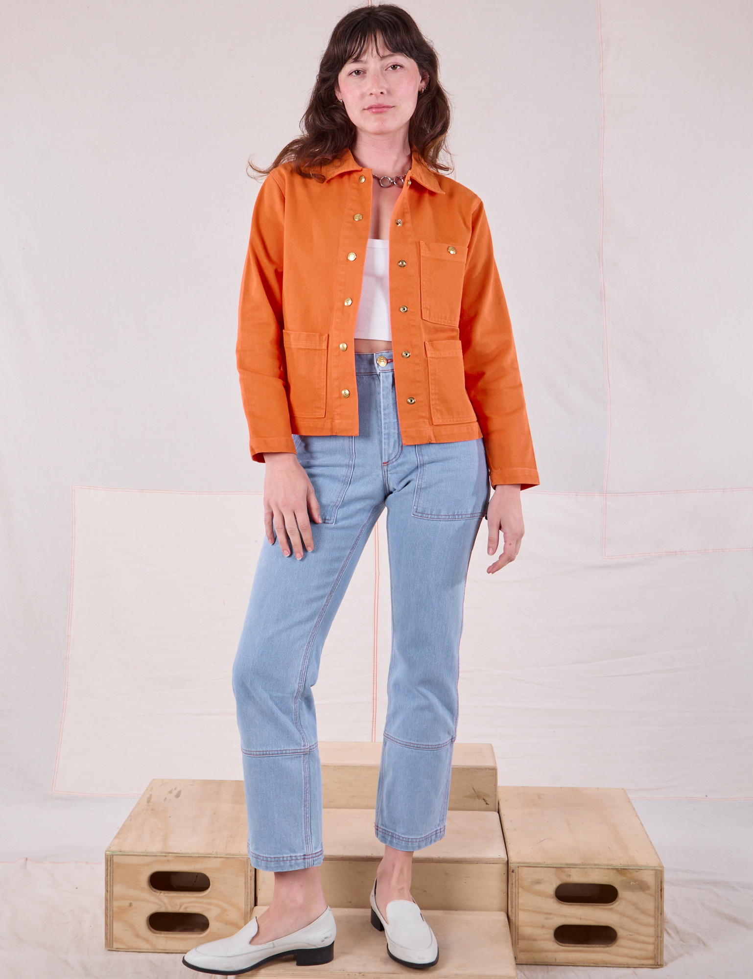 Alex is wearing Denim Work Jacket in Construction Orange and light wash Carpenter Jeans