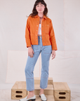 Alex is wearing Denim Work Jacket in Construction Orange and light wash Carpenter Jeans