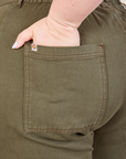 Work Pants in Surplus Green back pocket close up. Ashley has her hand in the pocket.