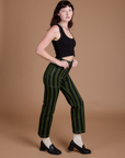 Side view of Black Stripe Work Pants in Evergreen and black Cropped Tank on Alex