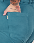Bell Bottoms in Marine Blue back pocket close up. Sam has their hand in the pocket.