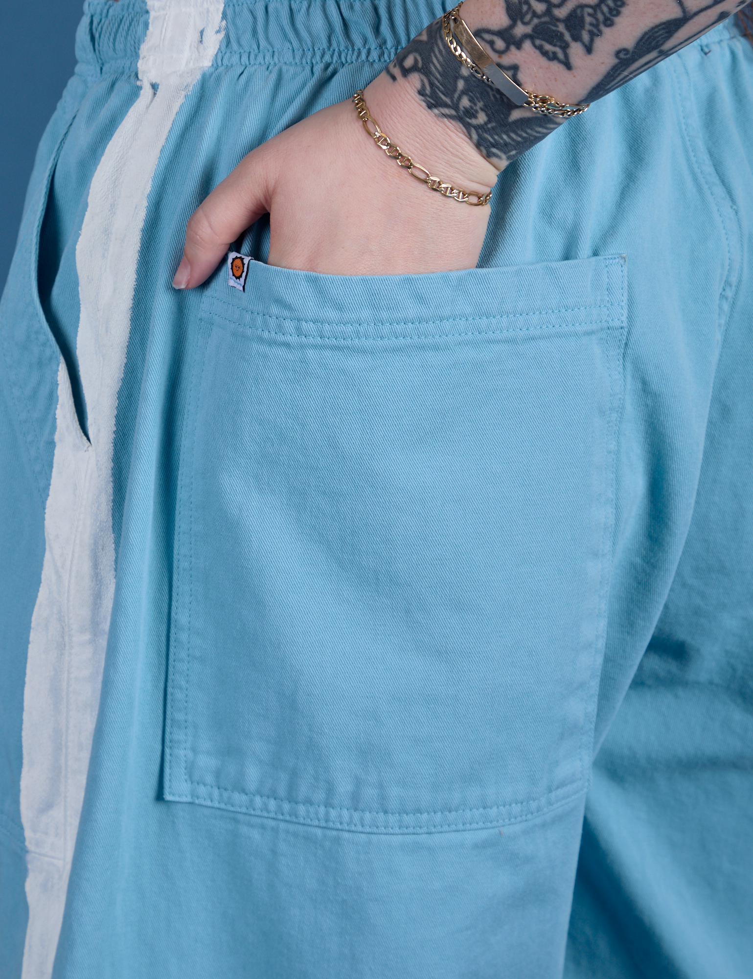 Close up of Sydney's hand in the back pocket of Painted Drop Pocket Cargo Pants in Baby Blue