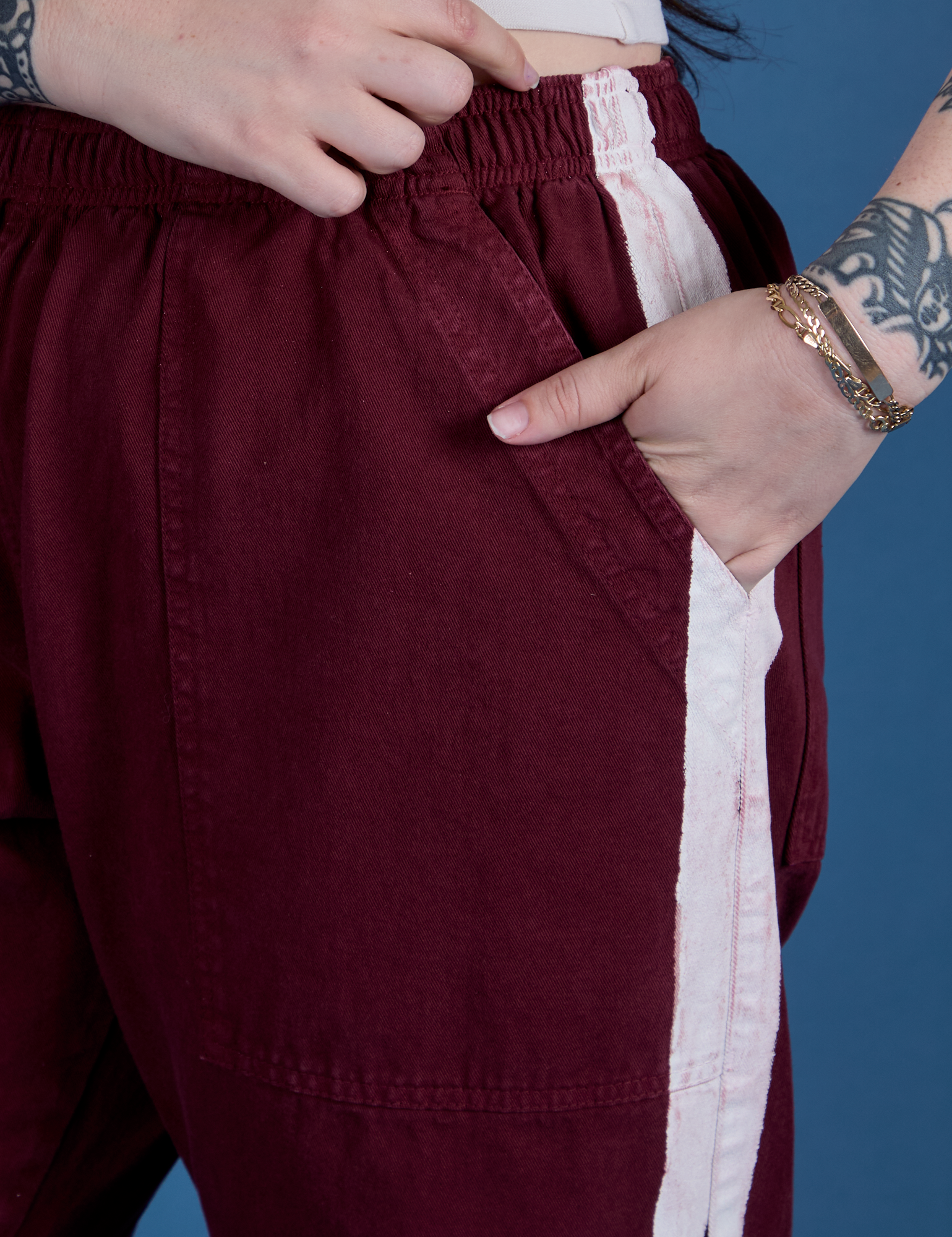 Close up of Sydney's hand in the front pocket of Painted Action Pants in Red Wine