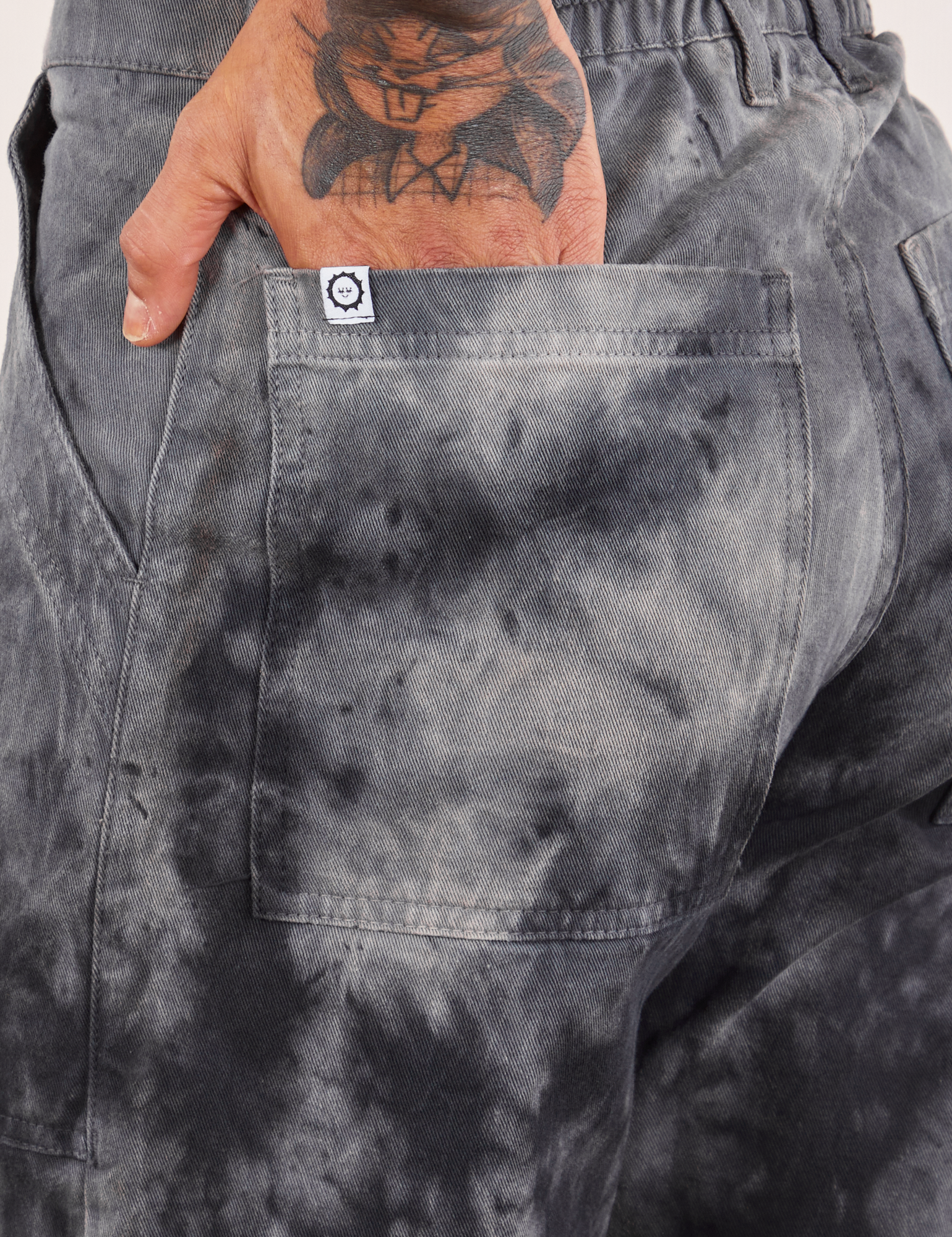 Back pocket close up of Black Magic Waters Work Pants. Jesse has their hand in the pocket.