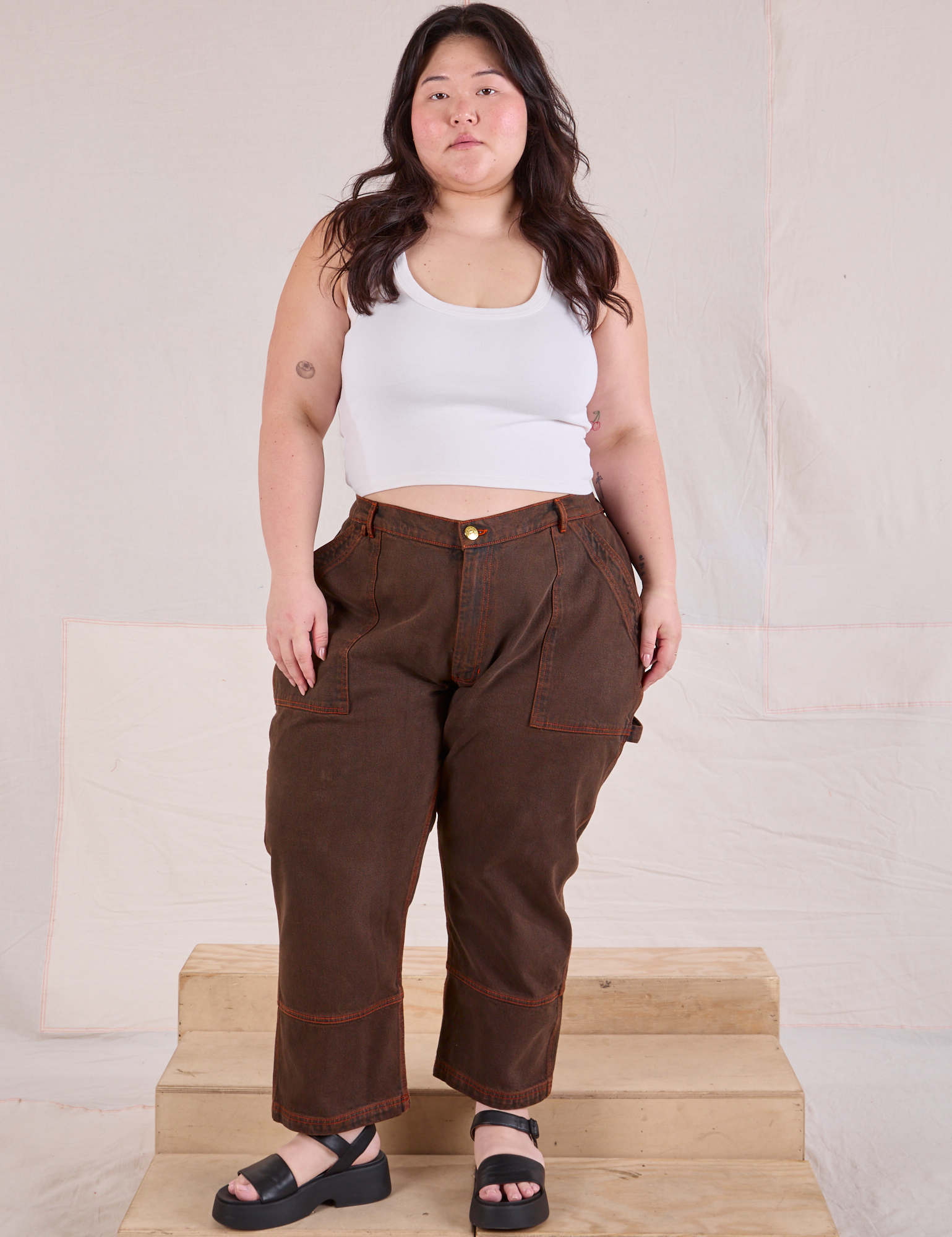 Ashley is 5&#39;7&quot; and wearing 1XL Petite Overdyed Carpenter Jeans in Fudge paired with Cropped Tank in vintage tee off-white