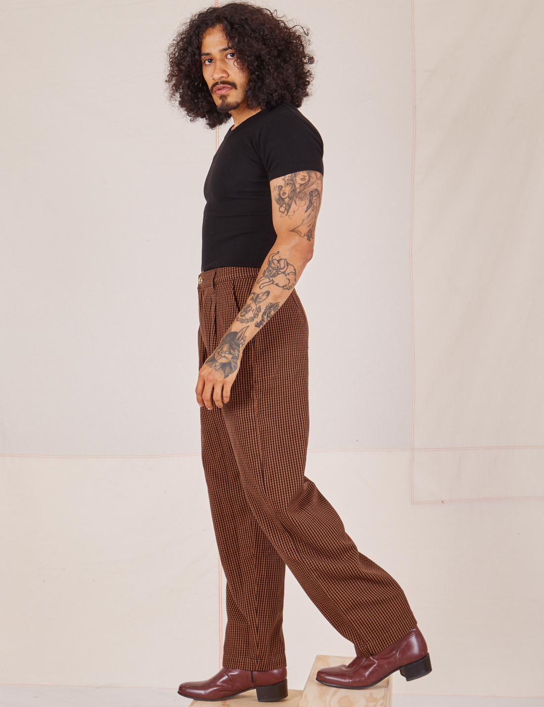 Side view of Checker Trousers in Brown and black Baby Tee worn by Jesse