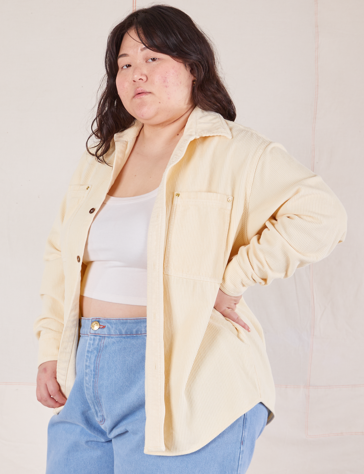 Angled front view of Corduroy Overshirt in Vintage Off-White with a vintage off-white Cropped Cami worn underneath and light wash Denim Trouser Jeans