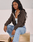Kandia is wearing Cropped Zip Hoodie in Espresso Brown and light wash Carpenter Jeans