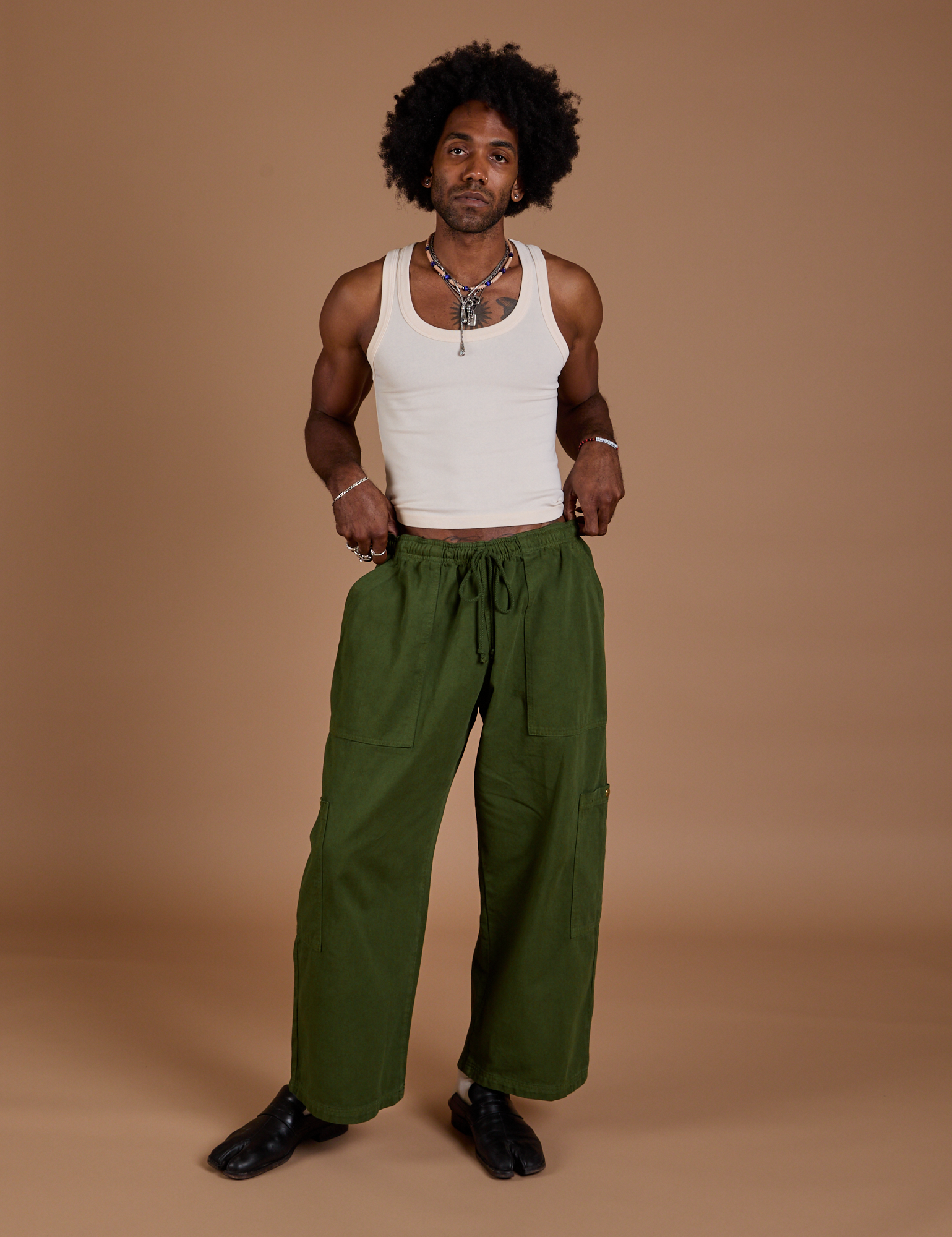 Jerrod is wearing Drop Pocket Cargo Pants in Evergreen and Tank Top in vintage tee white