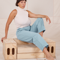Tiara is sitting on a stack of wooden crate. She is wearing Heavyweight Trousers in Baby Blue and vintage off-white Sleeveless Turtleneck.