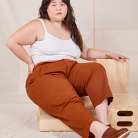 Ashley is sitting on a wooden crate. She is wearing Heavyweight Trousers in Burnt Terracotta and vintage off-white Cropped Cami