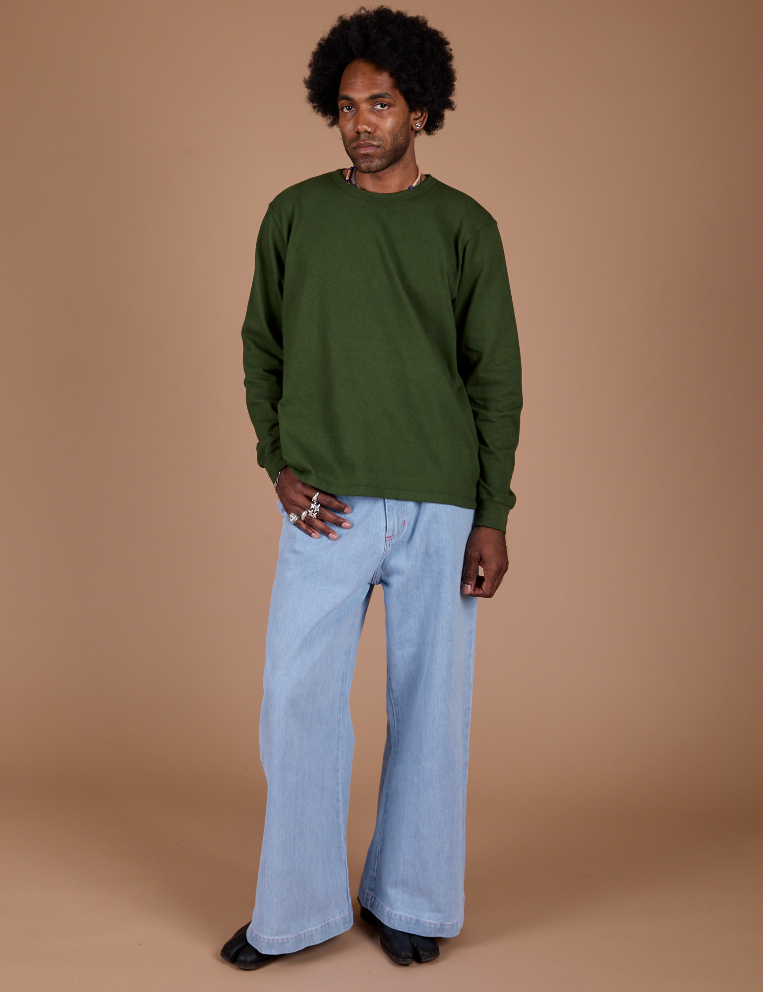 Jerrod is wearing Long Sleeve Burly Tee in Evergreen and light wash Indigo Wide Leg Trousers