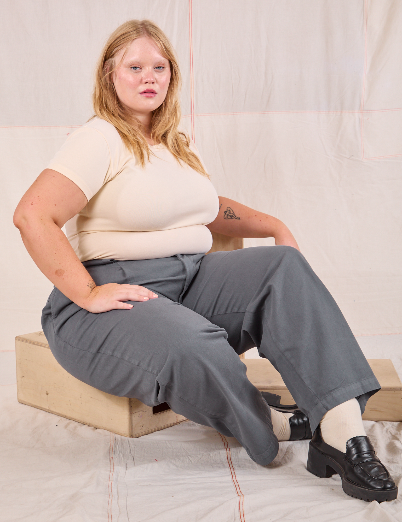 Juliet is wearing Mid-Rise Pleated Trousers in Slate Grey and Baby Tee in vintage tee off-white