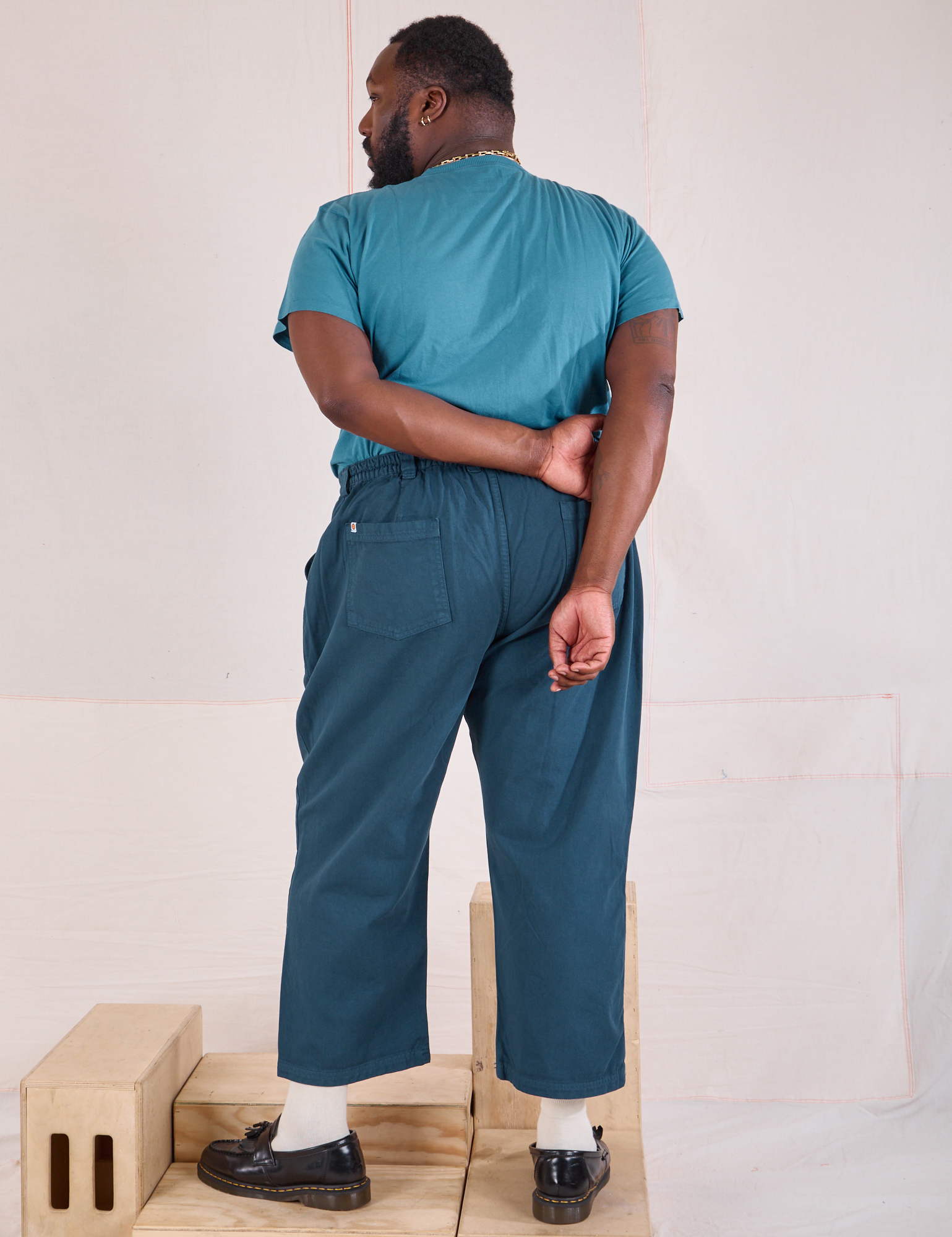 Back view of Mid-Rise Work Pants in Lagoon and marine blue Organic Vintage Tee on Elijah