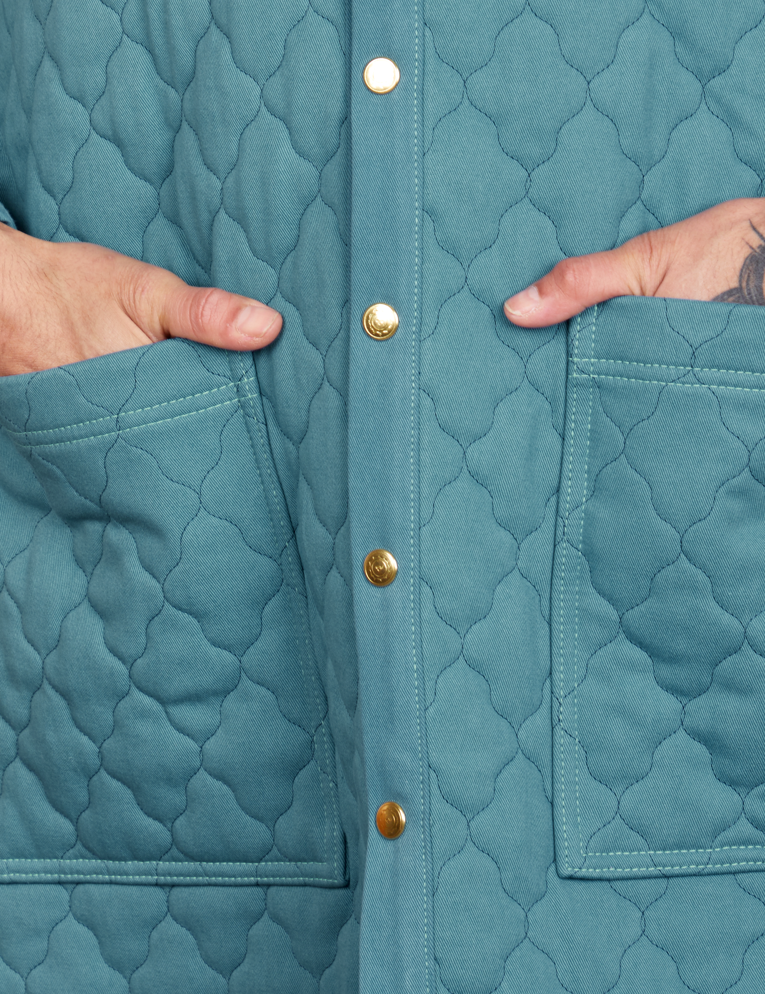 Front close up of Quilted Overcoat in Marine Blue. Jesse has their hand in the pockets.