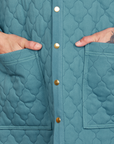 Front close up of Quilted Overcoat in Marine Blue. Jesse has their hand in the pockets.