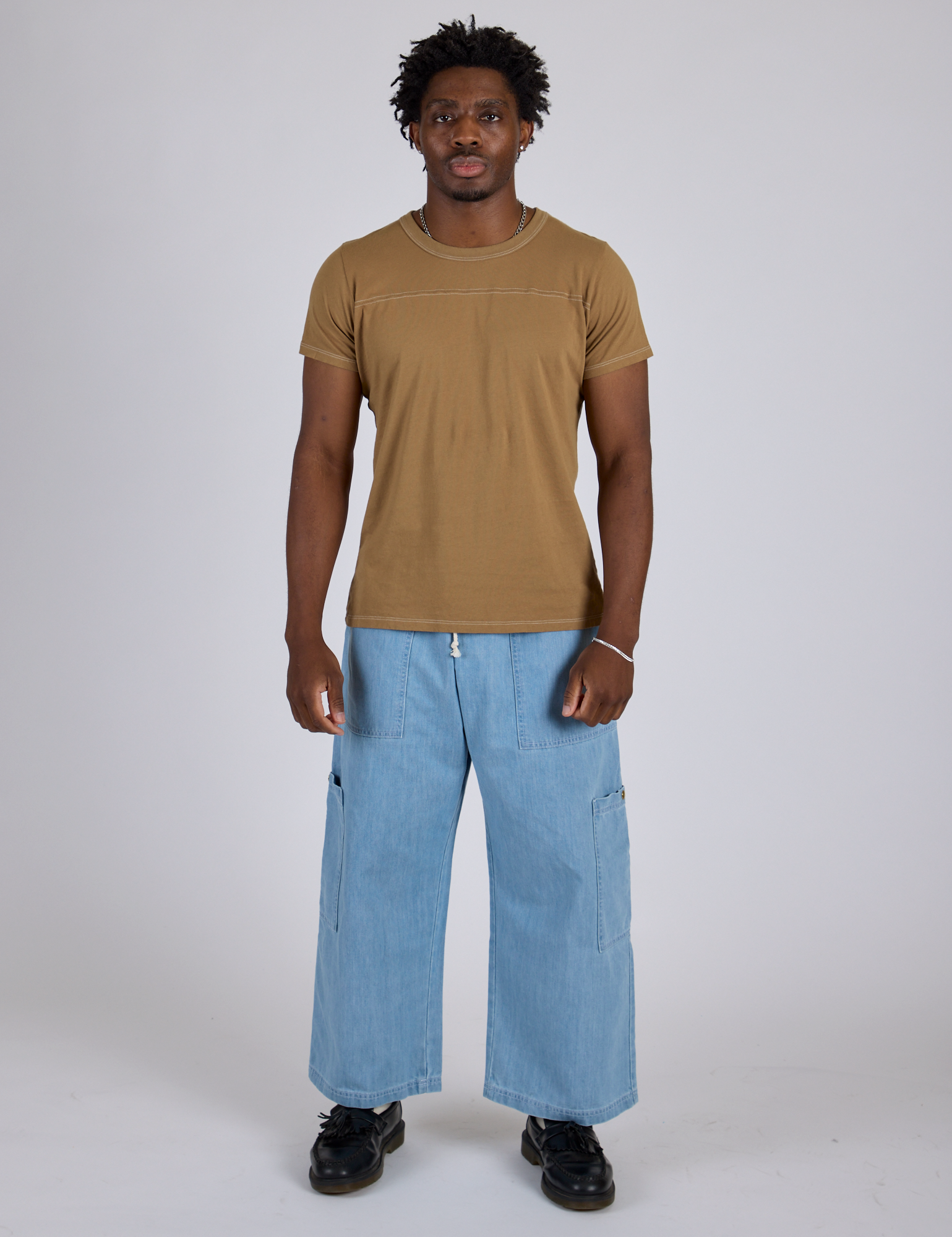Isaac is wearing Jr. Varsity Tee in Desert Brown and light wash Denim Drop Pocket Pants