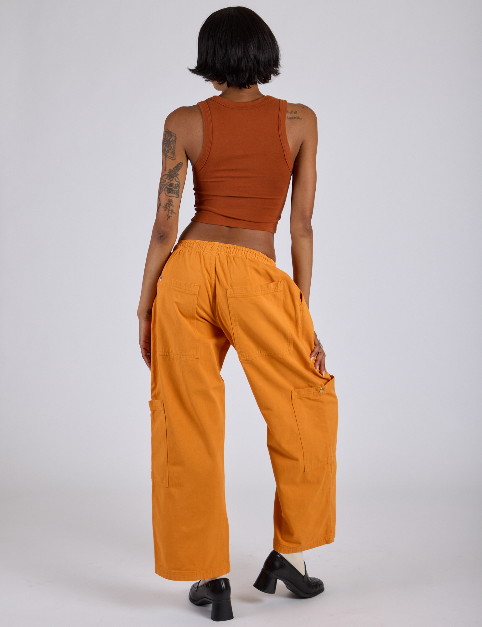 Back view of Drop Pocket Cargo Pants in Creamsicle Orange and burnt terracotta Cropped Tank on Kira