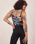 Back view of Cropped Cami in Rainbow Magic Waters and black Western Pants worn by Jesse. They have their right hand in the back pant pocket.