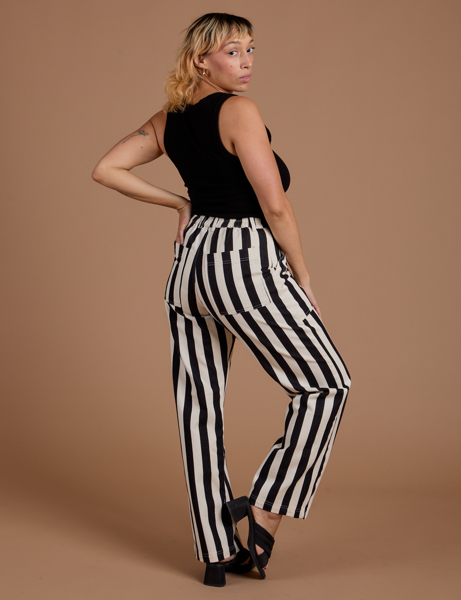 Angled back view of Black Stripe Work Pants in White and black Cropped Tank on Tiara
