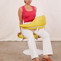 Mika is sitting in a yellow chair wearing Tank Top in Hot Pink and vintage off-white Western Pants