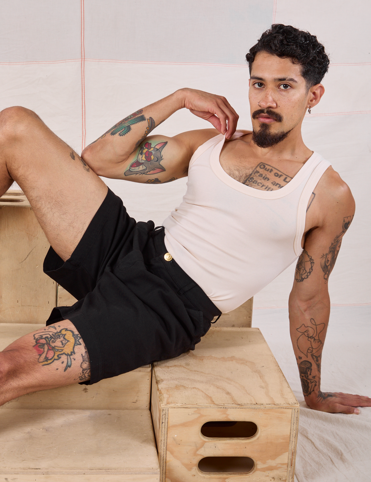 Jesse is wearing a Tank Top in vintage tee off-white and Trouser Shorts in Basic Black