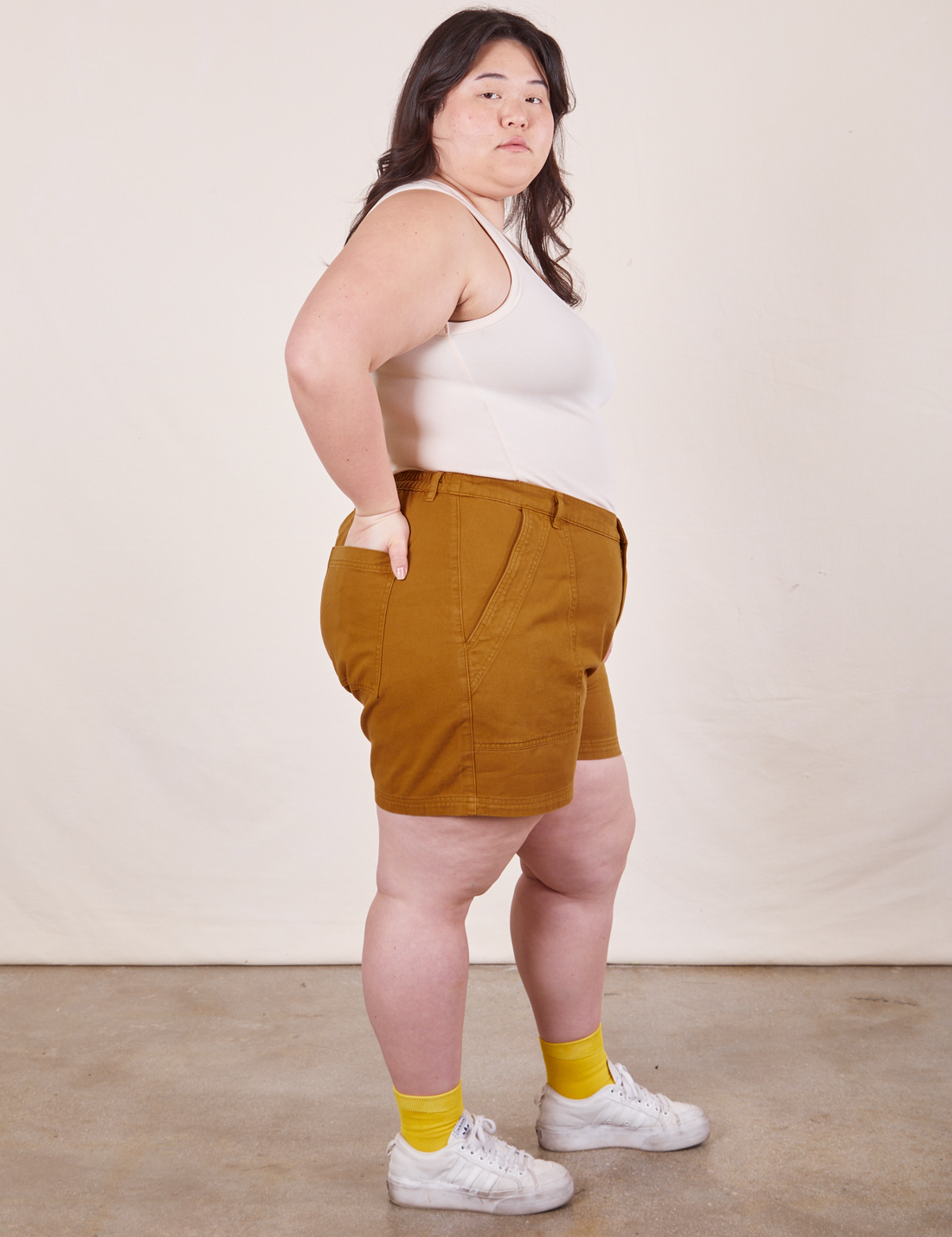 Side view of Classic Work Shorts in Spicy Mustard and vintage off-white Tank Top worn by Ashley