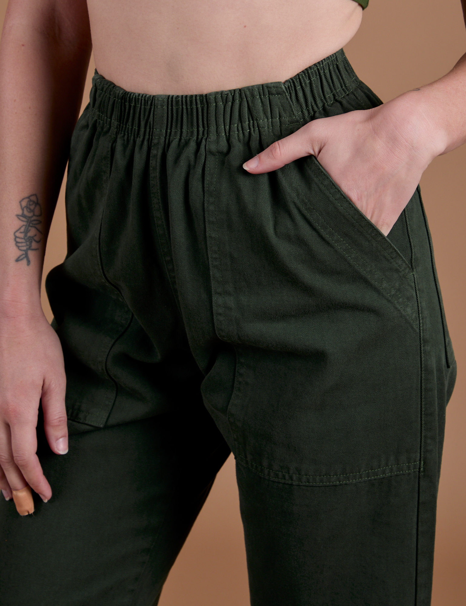 Close up of Alex's hand in the front pocket of Action Pants in Swamp Green