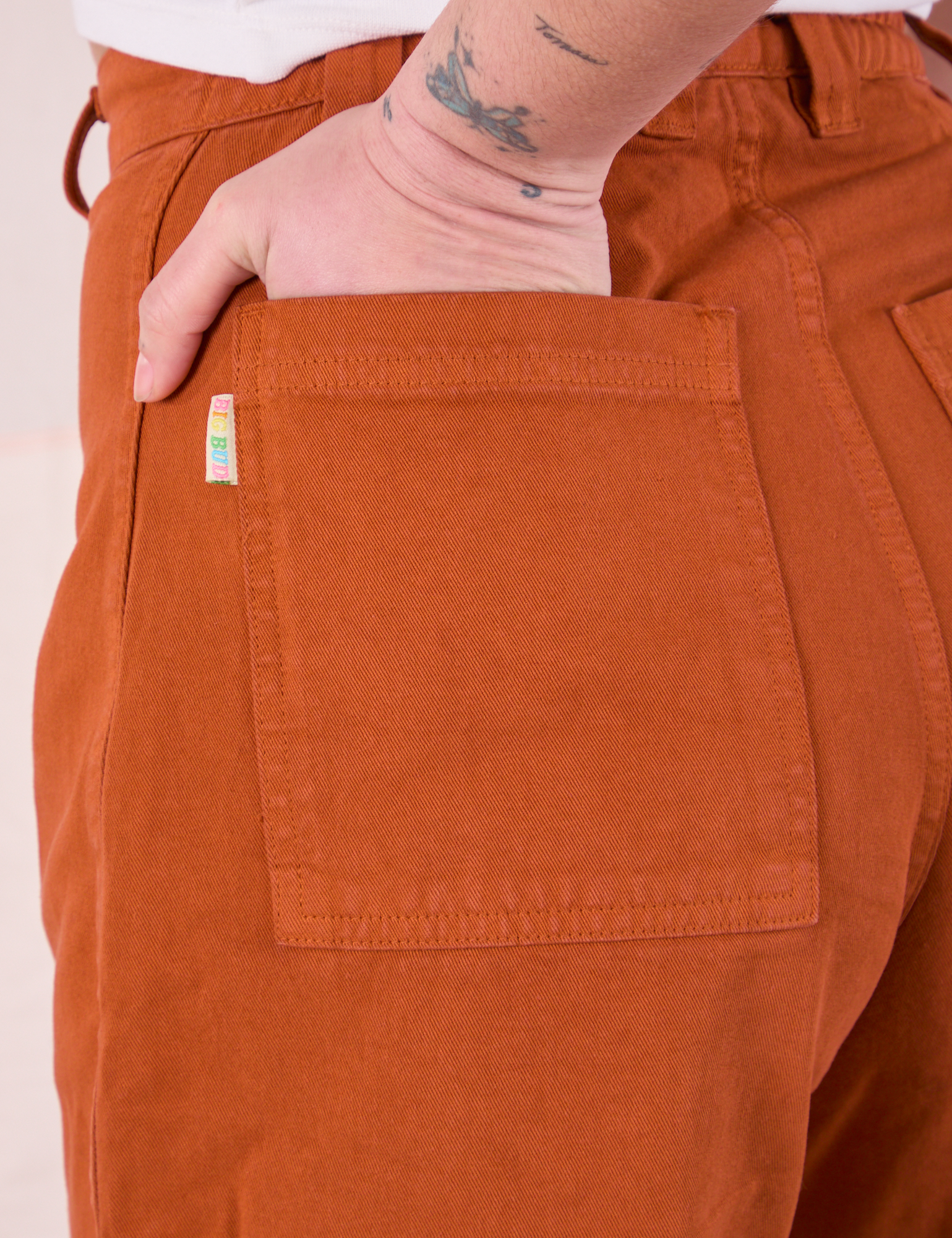 Close up of Betty&#39;s hand in the back pocket of Bell Bottoms in Burnt Terracotta