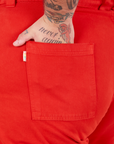 Bell Bottoms in Mustang Red back pocket close up. Sam has their hand in the pocket.