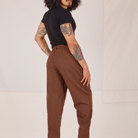 Angled back view of Checker Trousers in Brown and black Baby tee worn by Jesse
