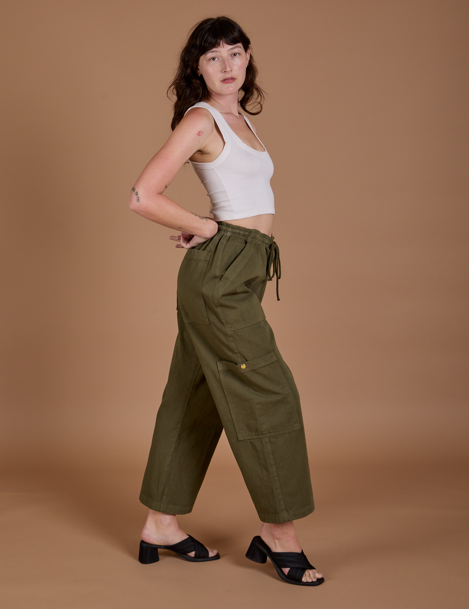 Side view of Drop Pocket Cargo Pants in Surplus Green and Cropped Tank in vintage tee white on Alex