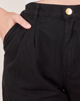 Front close up of Heavyweight Trousers in Basic Black. Alex has her hand in the pocket.
