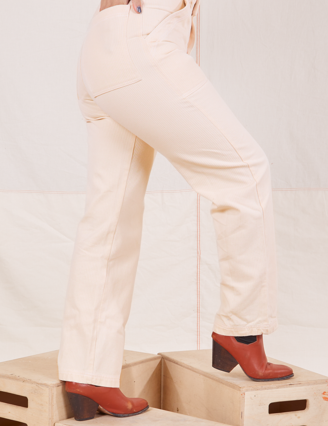 Heritage Short Sleeve Jumpsuit in Vintage Off-White side view close up of pant legs. Worn by Tiara with hand in back pocket.