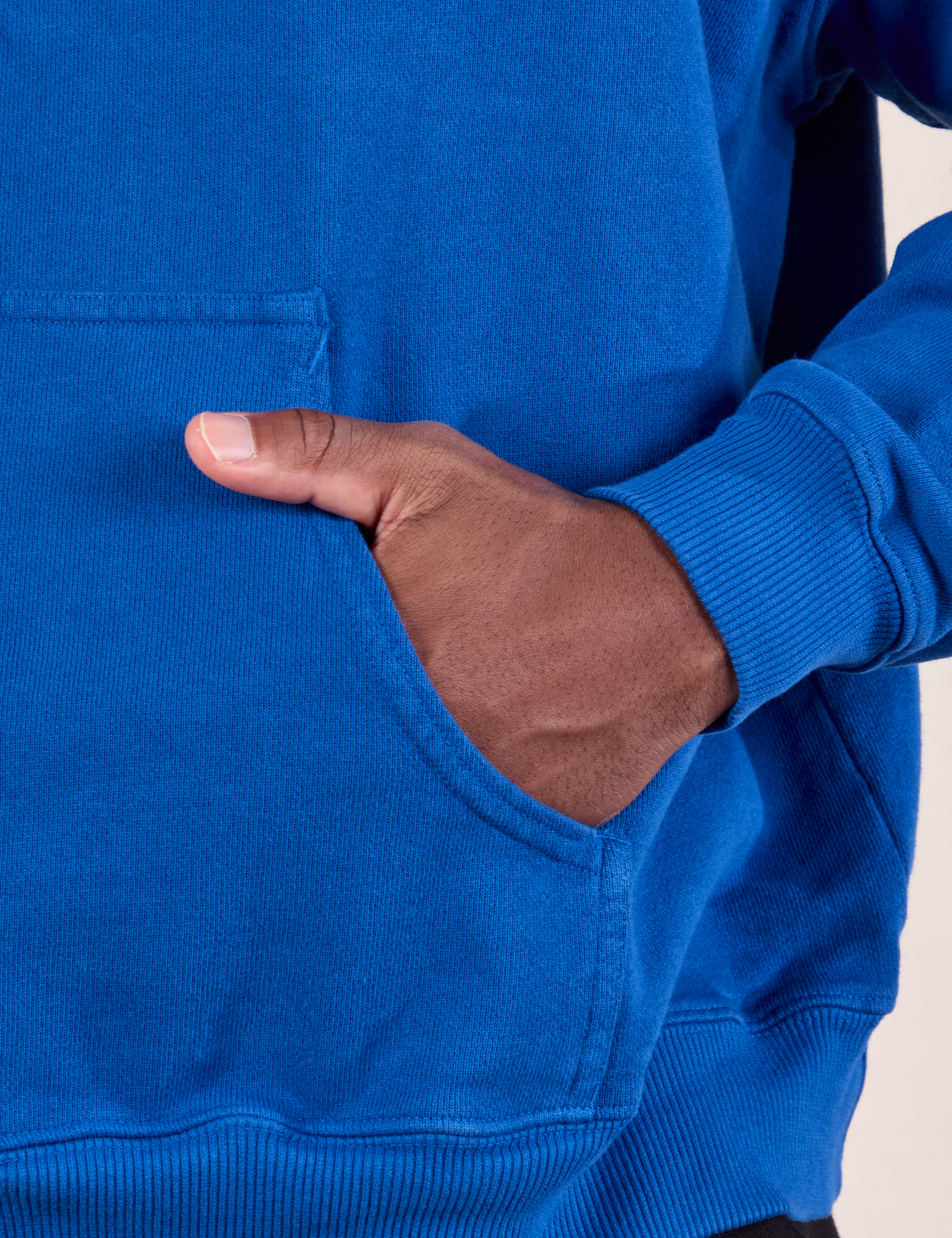 Oversized Hoodie in Royal Blue front pocket close up. Issac has his hand in the pocket.