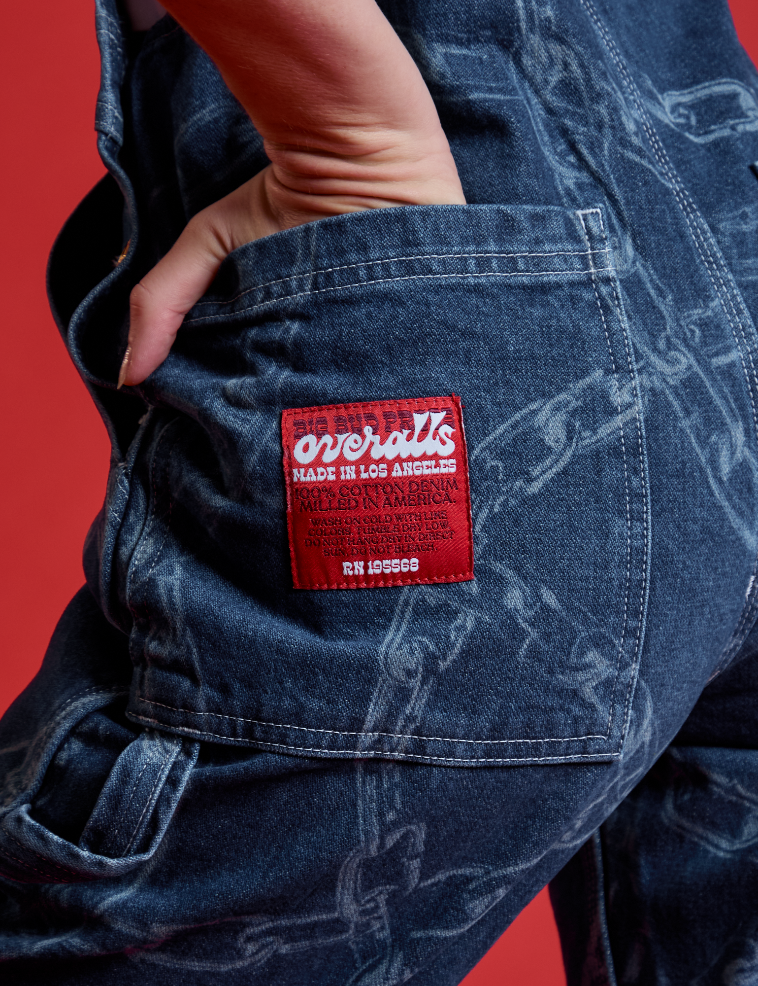 Close up of Alex&#39;s hand in the back pocket of Carpenter Overalls in Chain Link