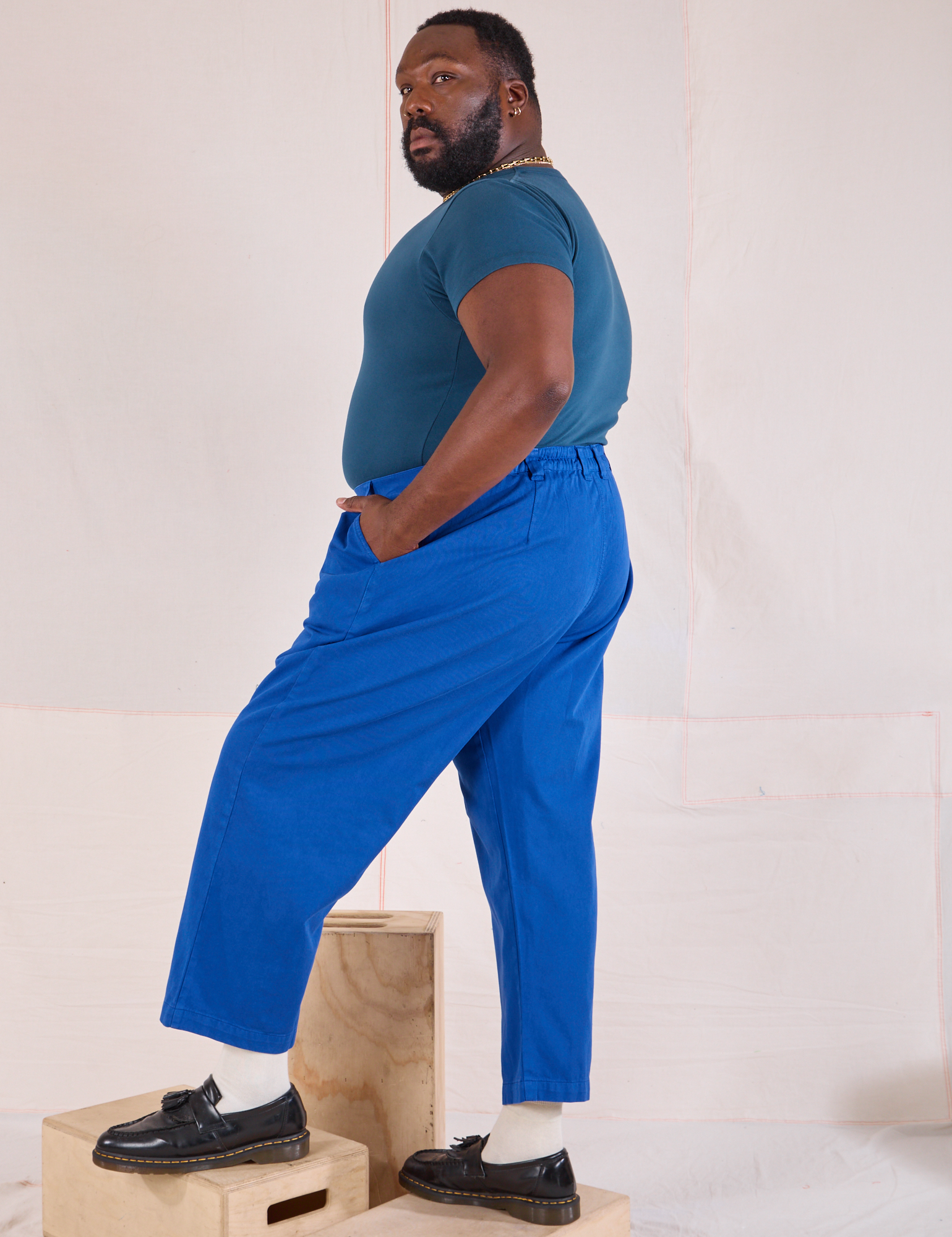 Side view of Mid-Rise Pleated Trousers in Royal Blue and lagoon Baby Tee on Elijah