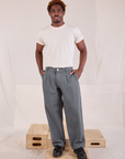 Issac is 5'10" and wearing M Mid-Rise Pleated Trousers in Slate Grey paired with Organic Vintage Tee in vintage tee off-white